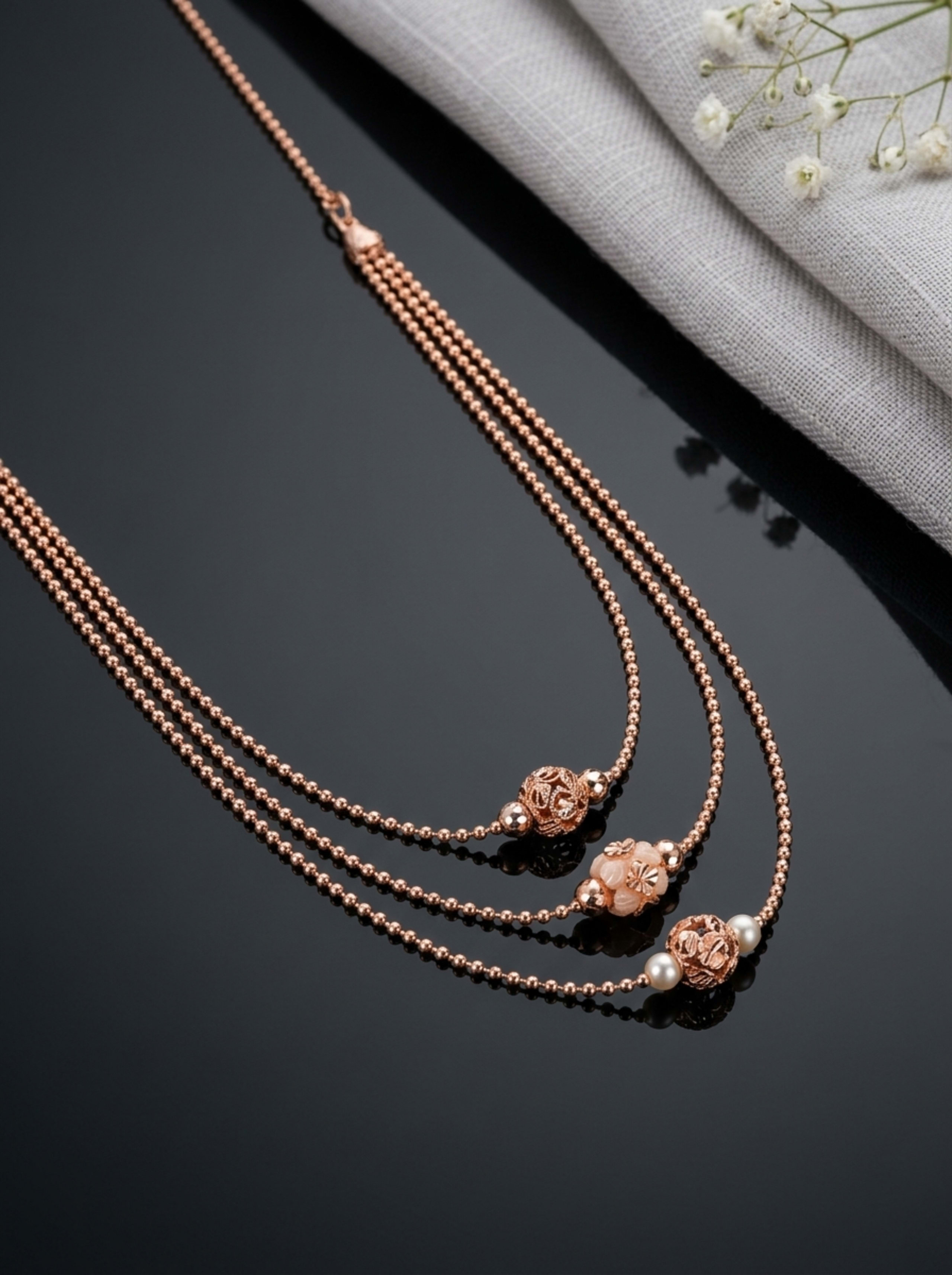 Triple-Tier Diamond-Cut Bead Layered Chain in 18KT rose gold on glossy black surface