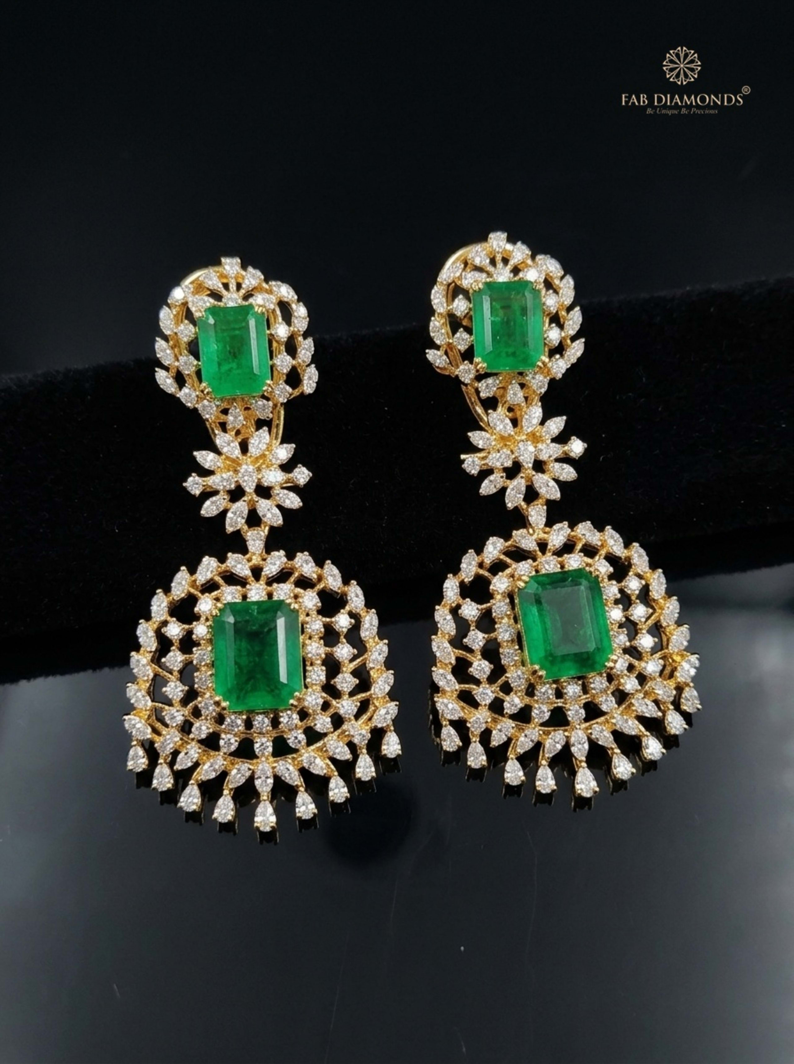 Twin Pear Emerald Tiara Starburst Drop Earrings on dark charcoal stone blocks