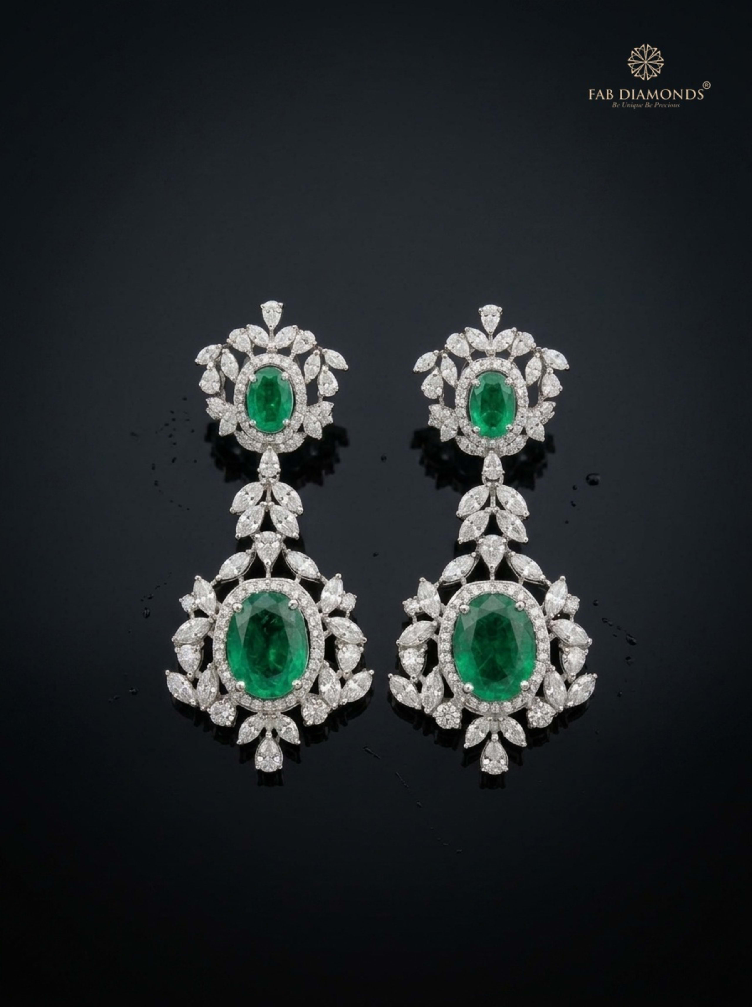Royal emerald and diamond chandelier drop earrings on glossy black obsidian with water reflections