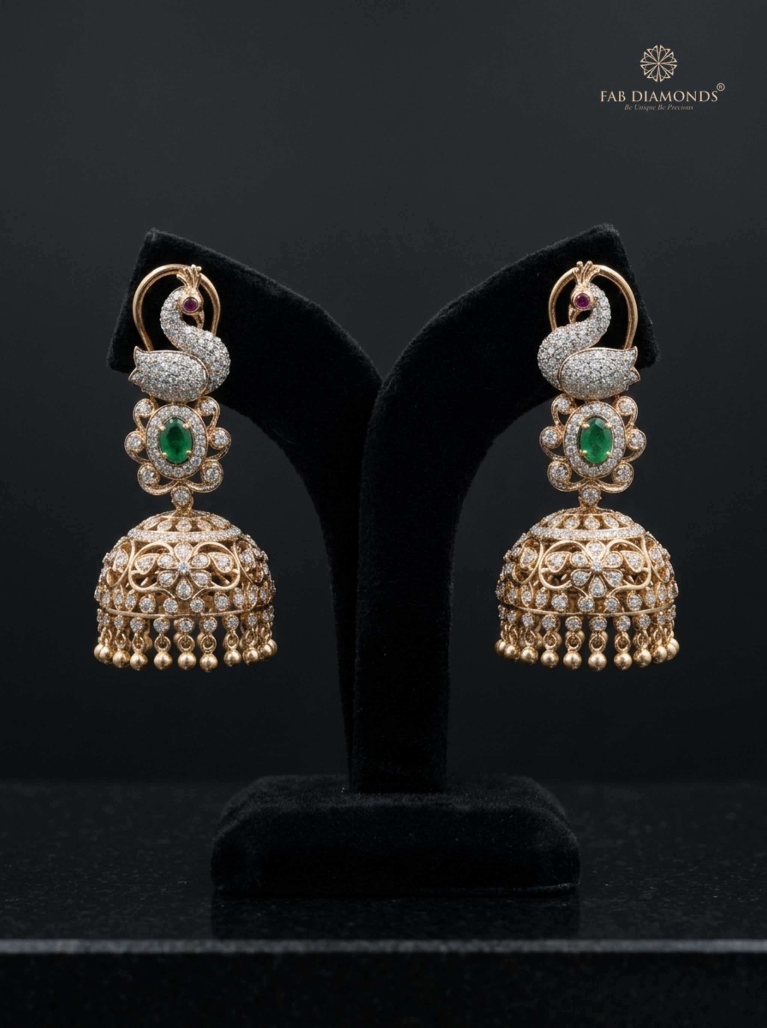 A pair of Nithya diamond mayura peacock jhumkas on rustic dark timber with rose petals
