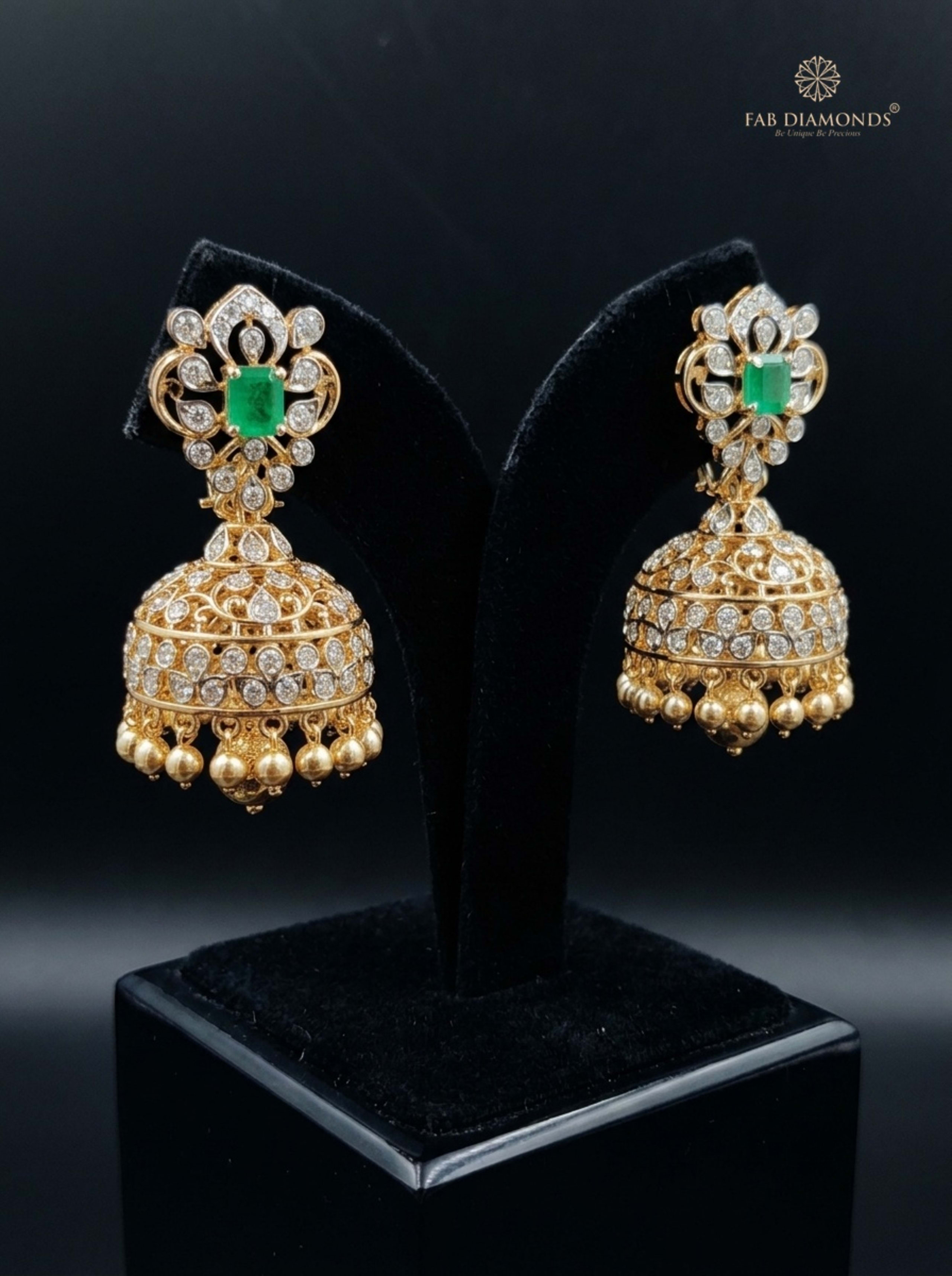 A pair of Kalyani royal foliate emerald diamond jhumkas on champagne silk cushion