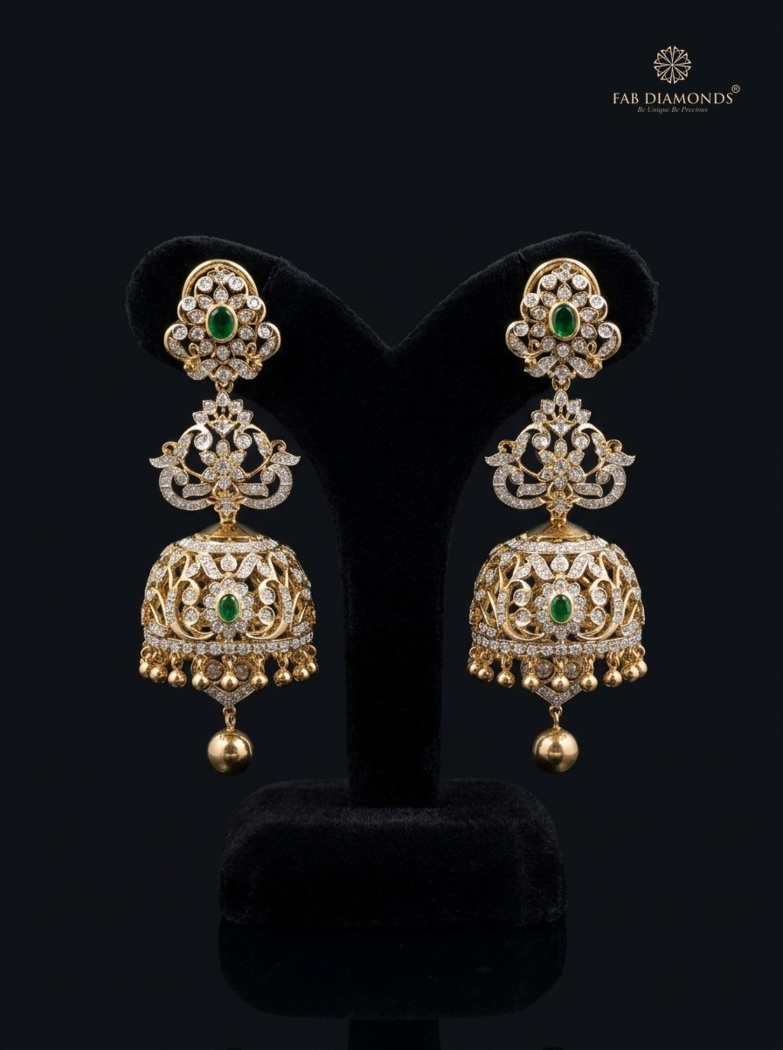 A pair of Chandra winged scroll diamond jhumkas on black surface with botanical foliage