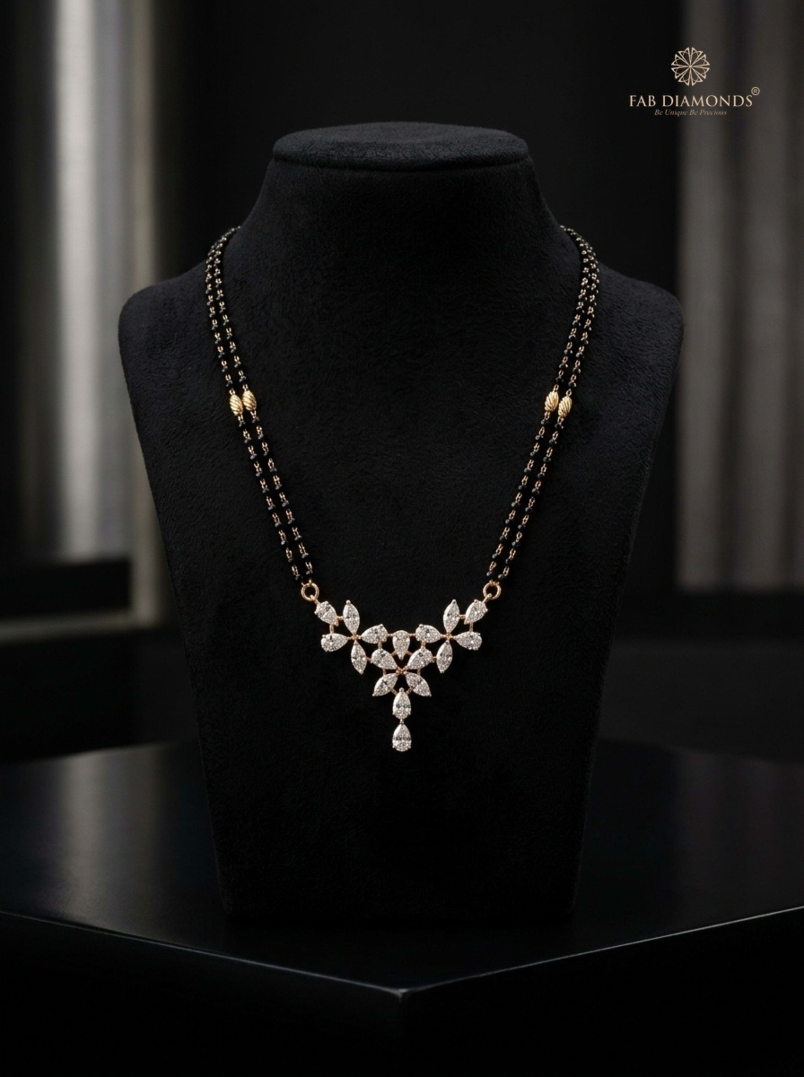 Devika marquise and pear diamond cluster mangalsutra held in model hands over champagne velvet