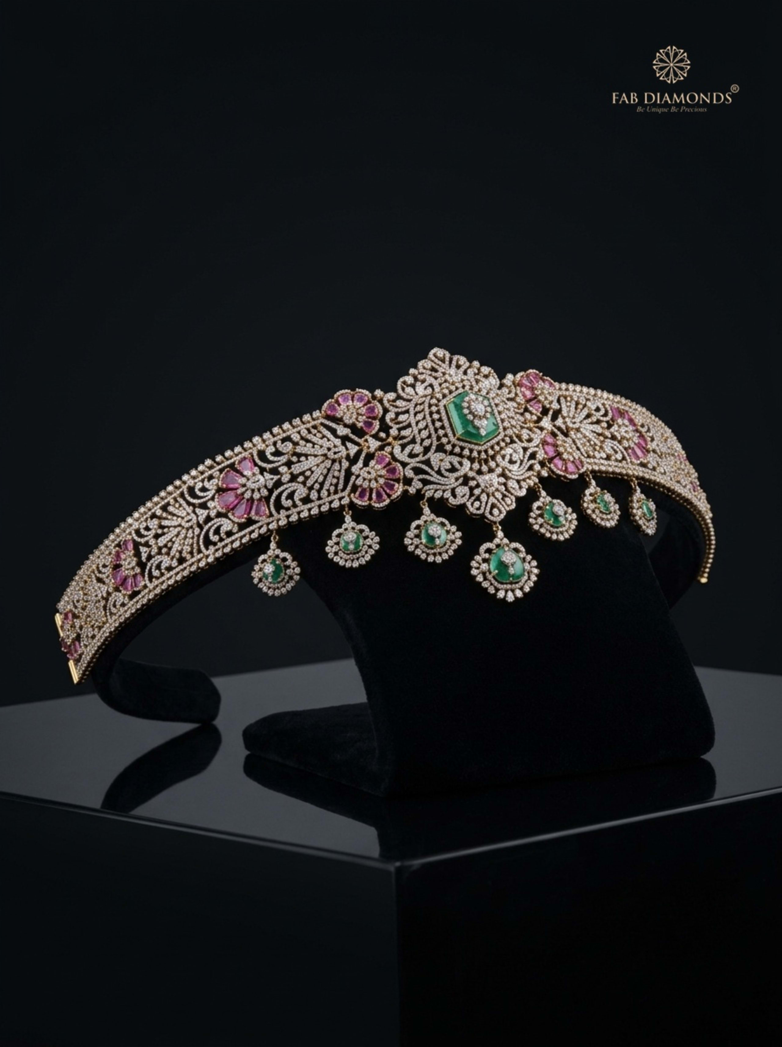 Kanchi pink sapphire, emerald, and diamond vaddanam on dark graphite plinth with foliage