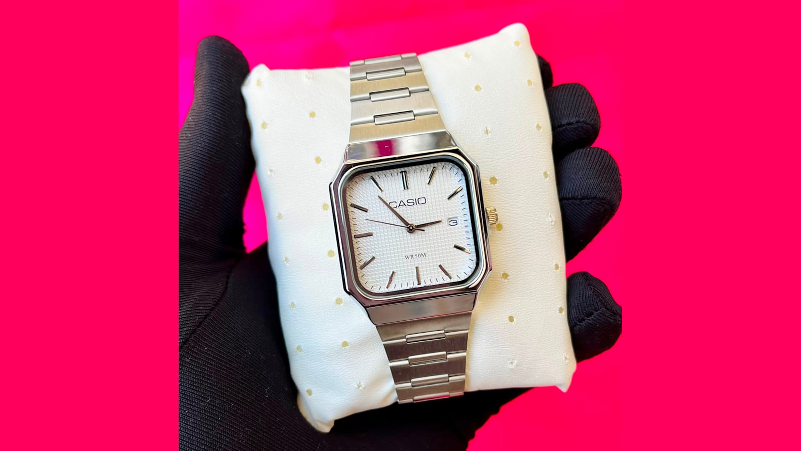 Casio rectangular analog watch with a white dial and stainless steel bracelet on a watch cushion