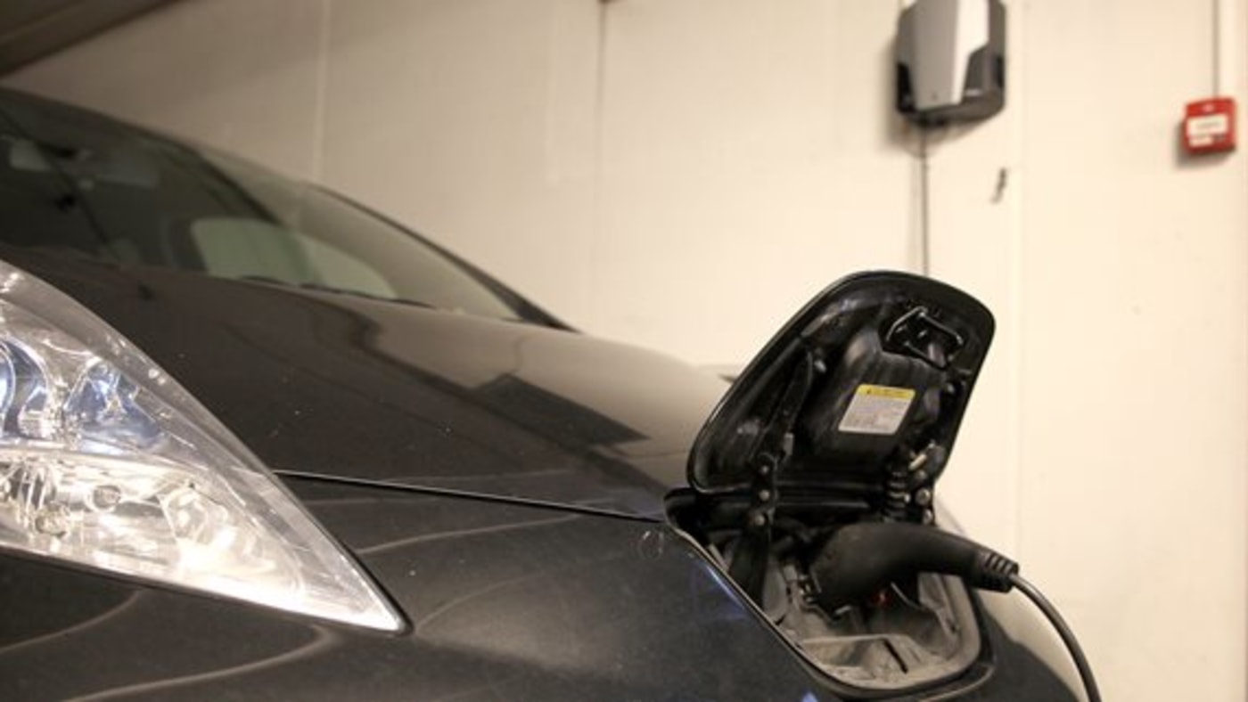En sort Nissan Leaf som lader i en garasje.