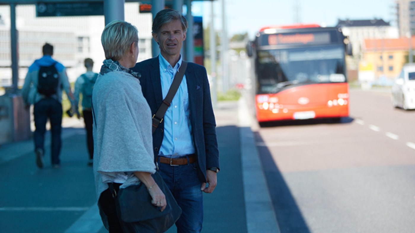 Mann og dame foran rød buss