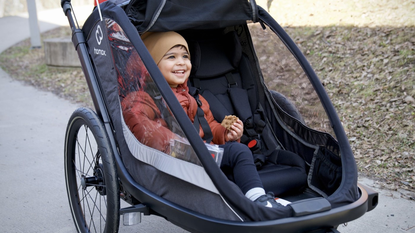 gutt smiler i grå sykkelvogn