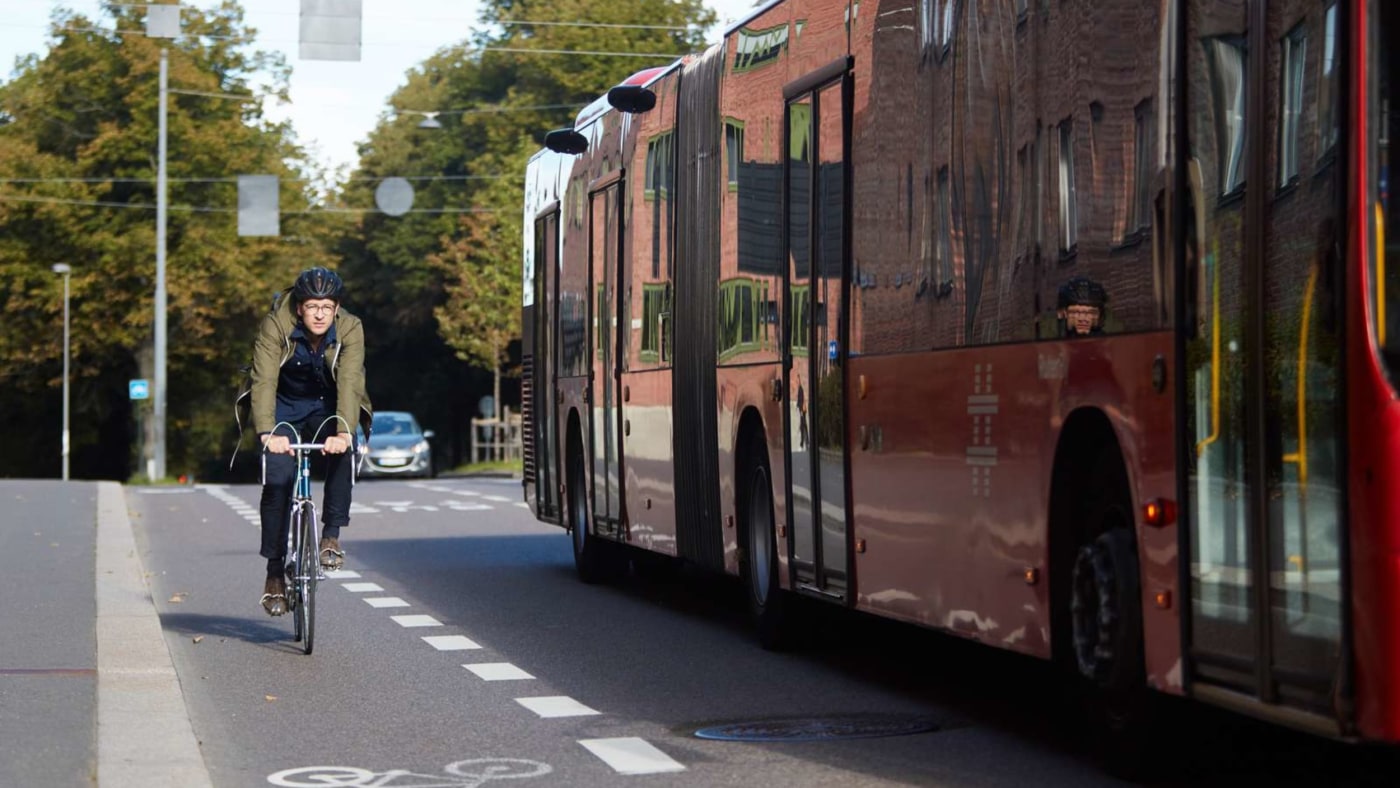 Syklist sykler i sykkelfeltet og buss passerer 