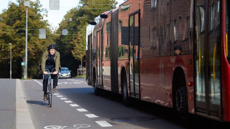 Syklist sykler i sykkelfeltet og buss passerer 
