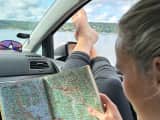 Kvinne sitter i bilen og kikker i NAF Veibok