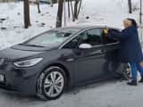Bildet viser en dame som skraper isen av bilen sin.