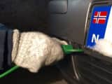 Bildet viser en mann som fester en elektrisk motorvarmer på bilen.