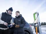 to mennesker som lader elbil ved ladestasjon