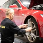 Mann tar service på rød elbil.