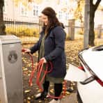 kvinne lader på kommunal ladestasjon