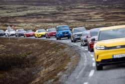 Kolonne av fargerike testbiler på fjellet
