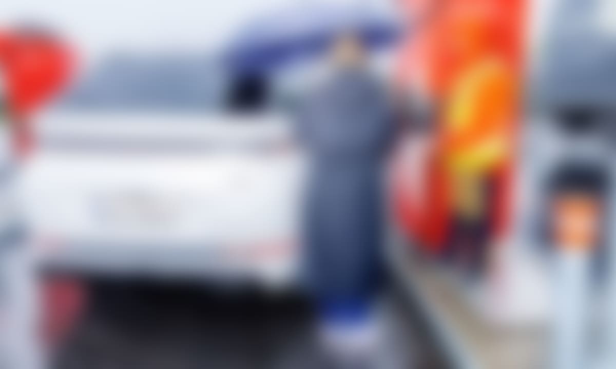 Hvit Xpeng X9 lades i høljregn mens gjennomvåte mennesker ser på