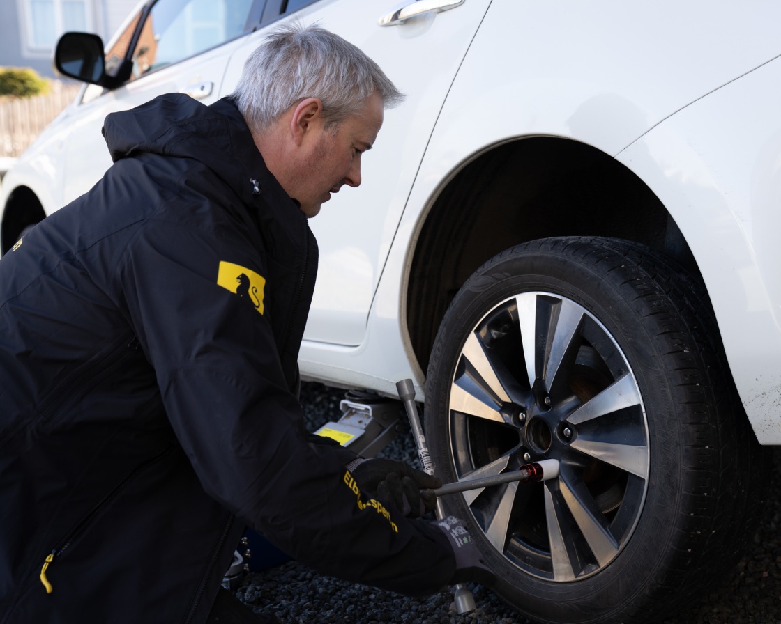 Mann skifter hjul på Nissan Leaf.