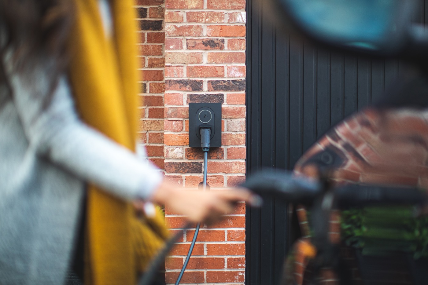 Jente lader bil med Zaptec lader tydelig i bakgrunnen