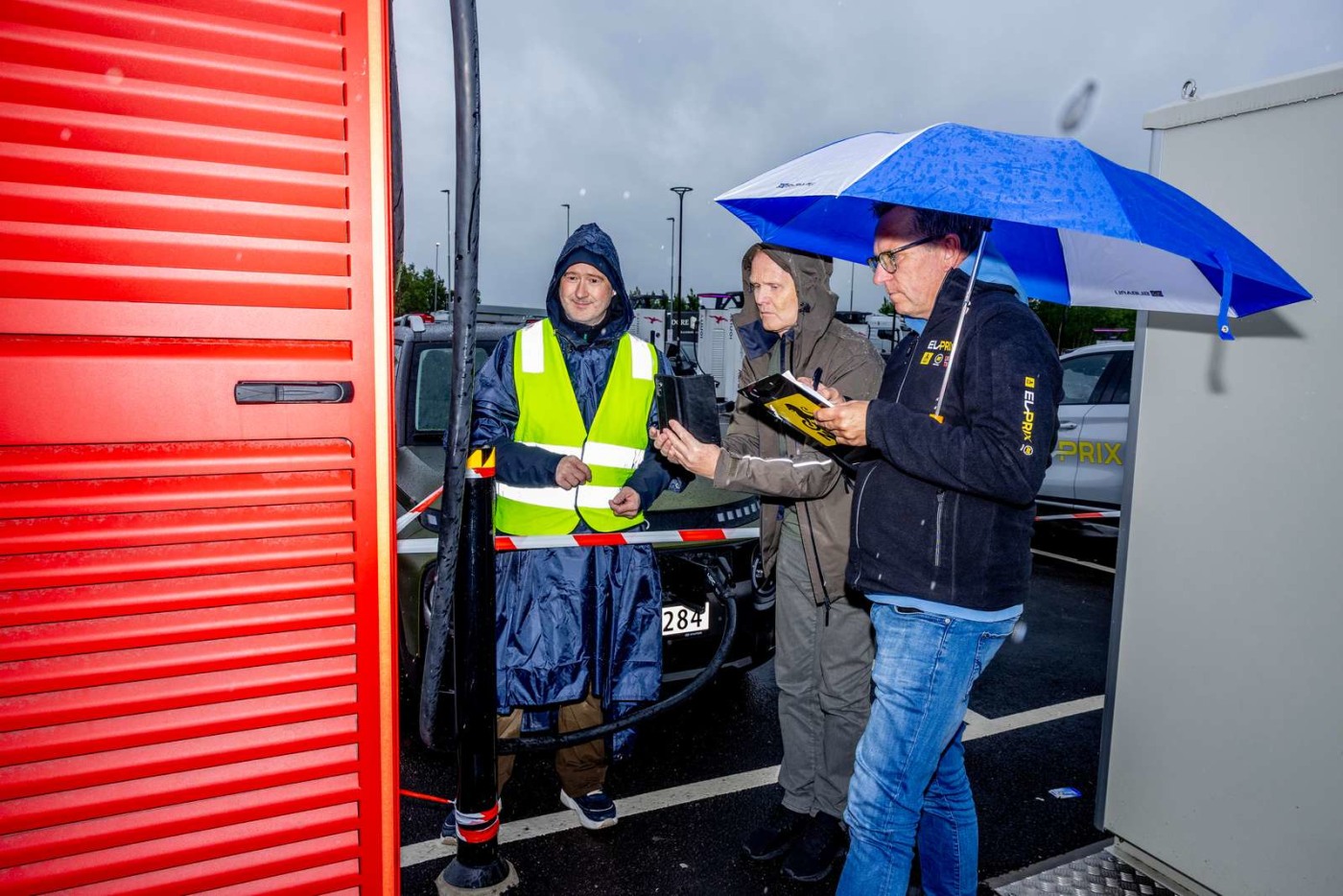 Ladetest av Hyundai Inster i høljregn med paraply og våte testsjåfører