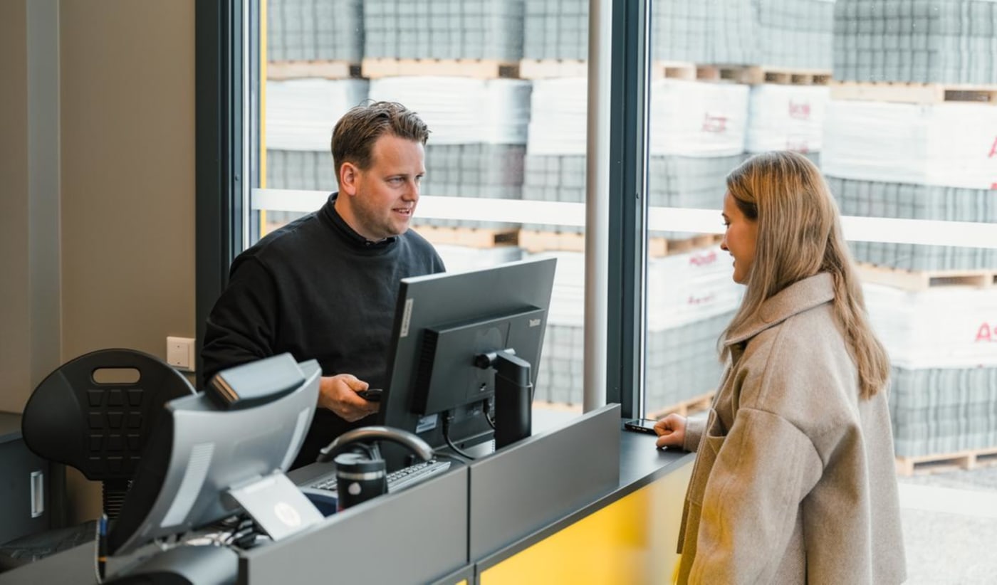 Mann på NAF-senter snakker med kunde over disk