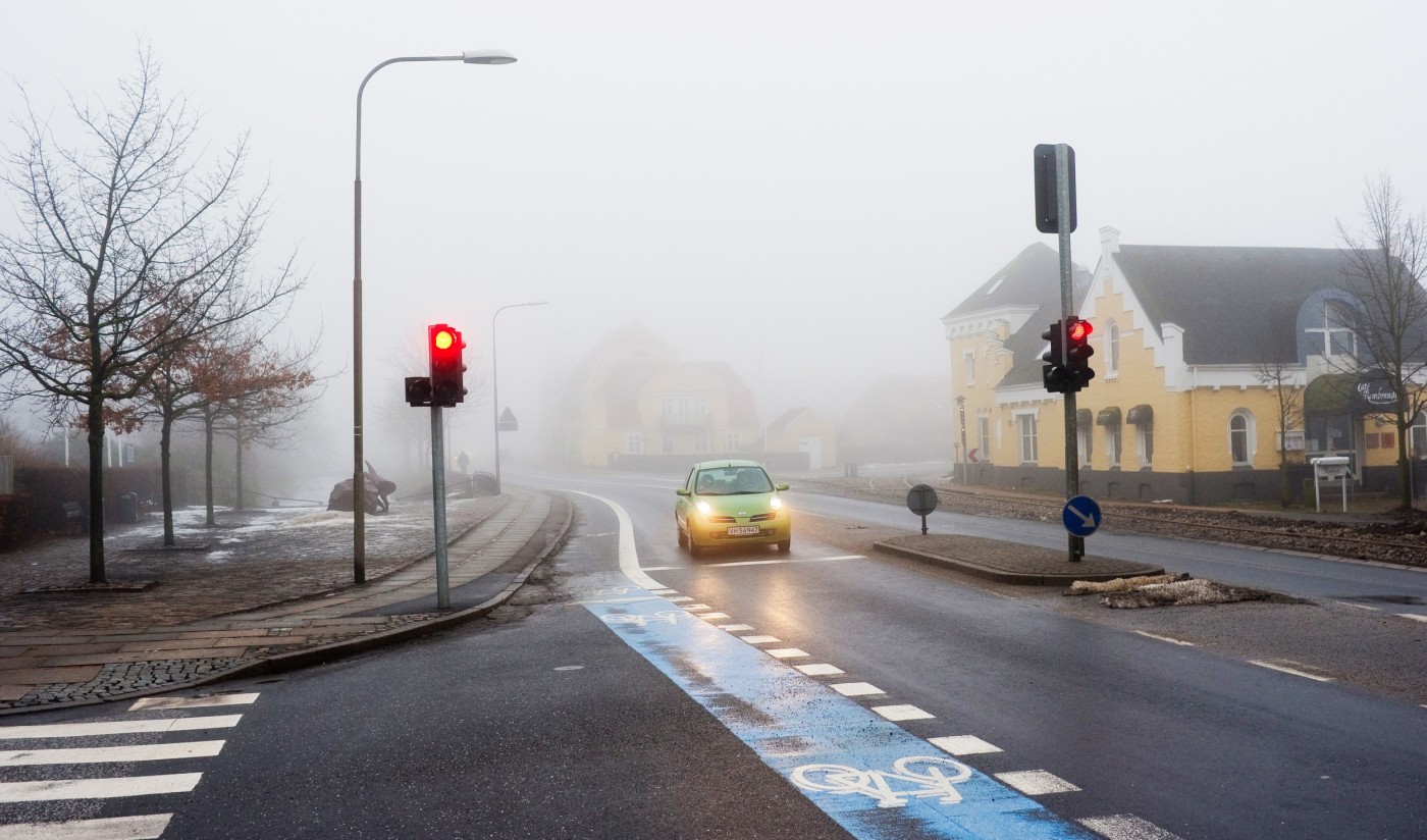 Bil står stille i trafikkryss mens den venter på grønt lys.