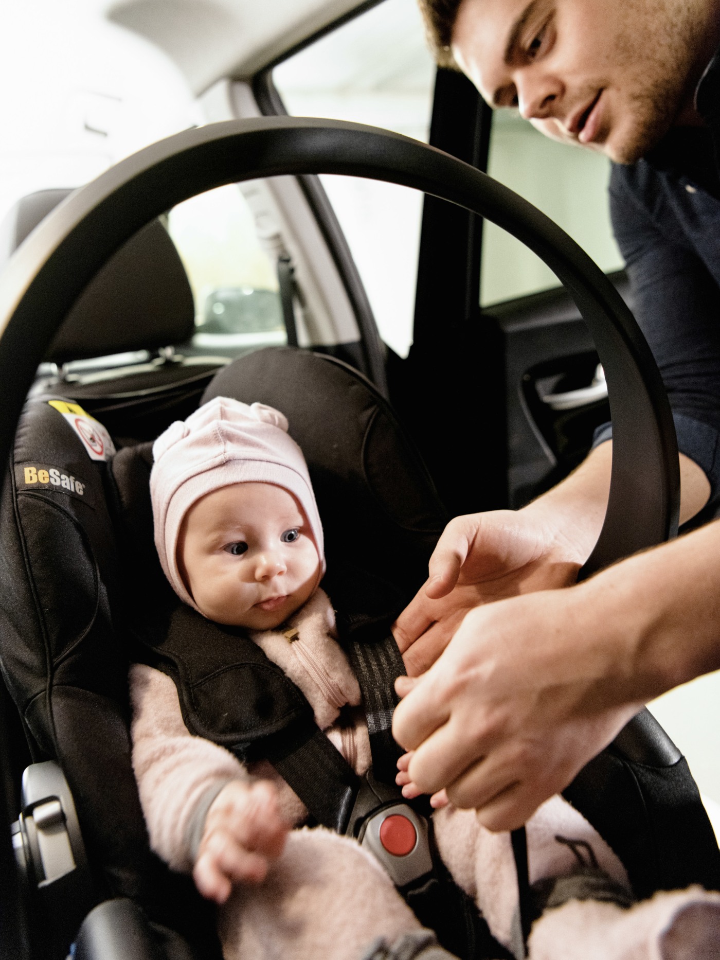mann fester setebelte på baby i barnesete