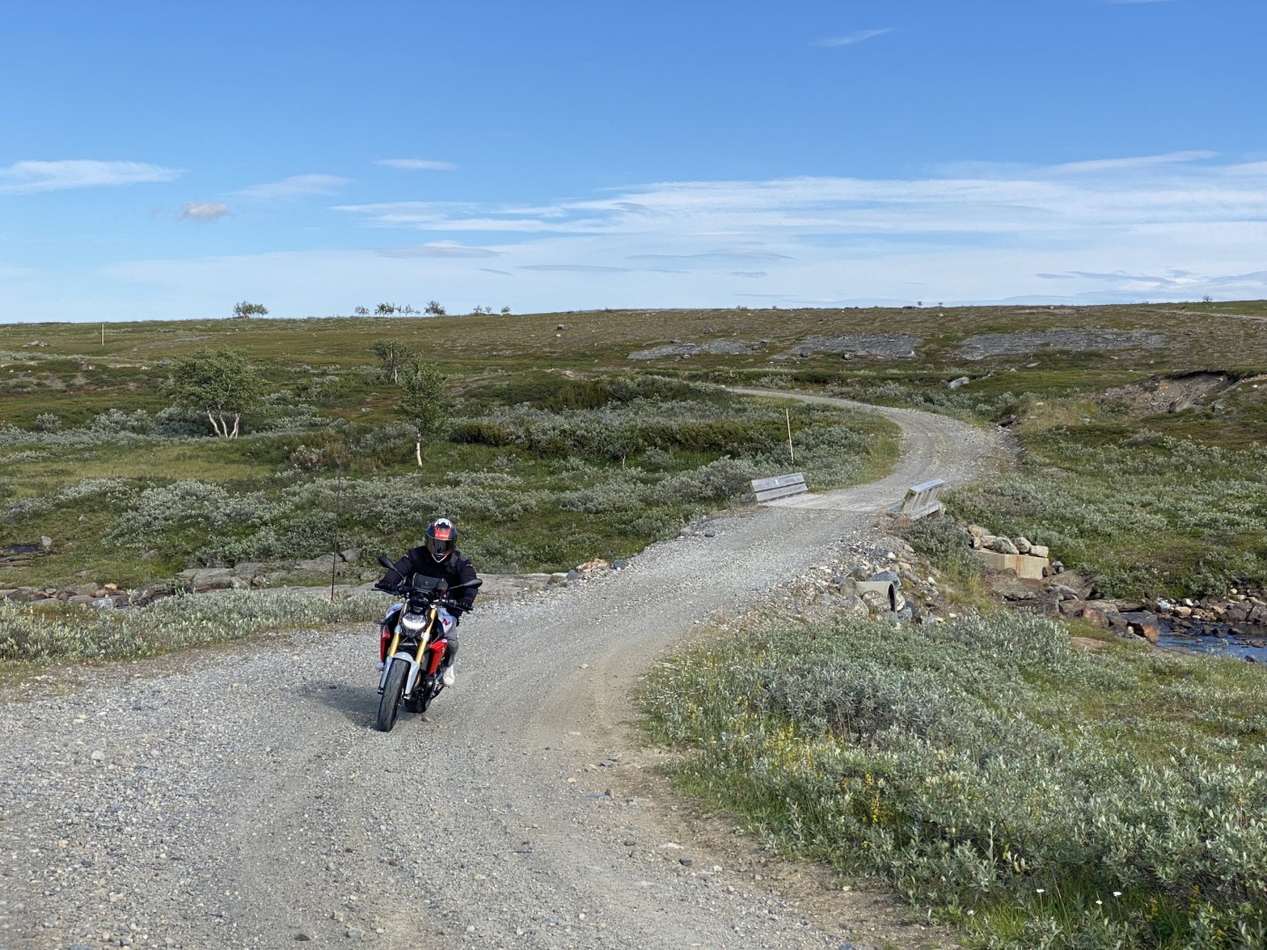 Mann på motorsykkel på Postruta, en gruslagt vei. 