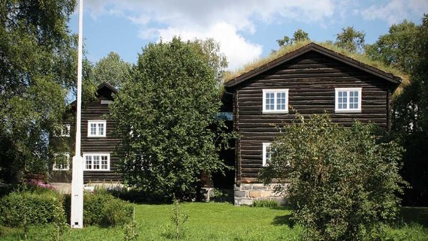Flere lafta hus, omringet av trær. 