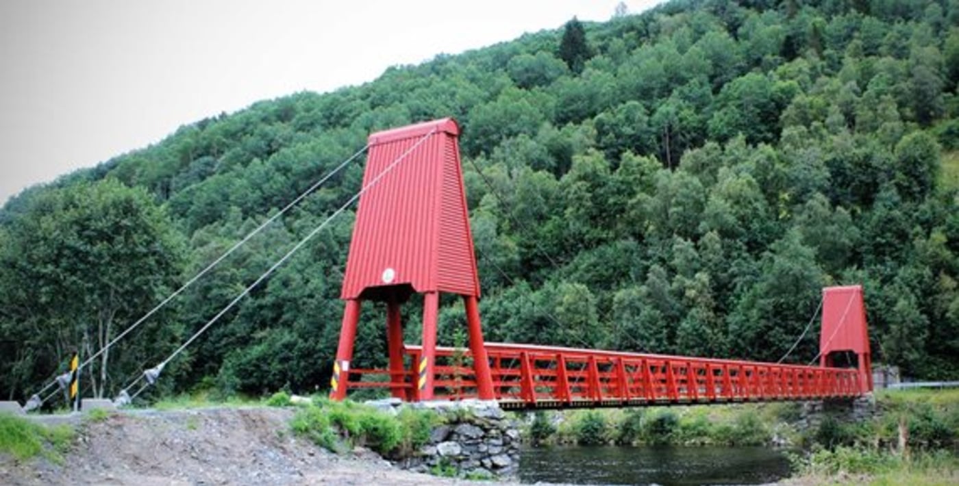 Bru over vann med frodig vegetasjon rundt.