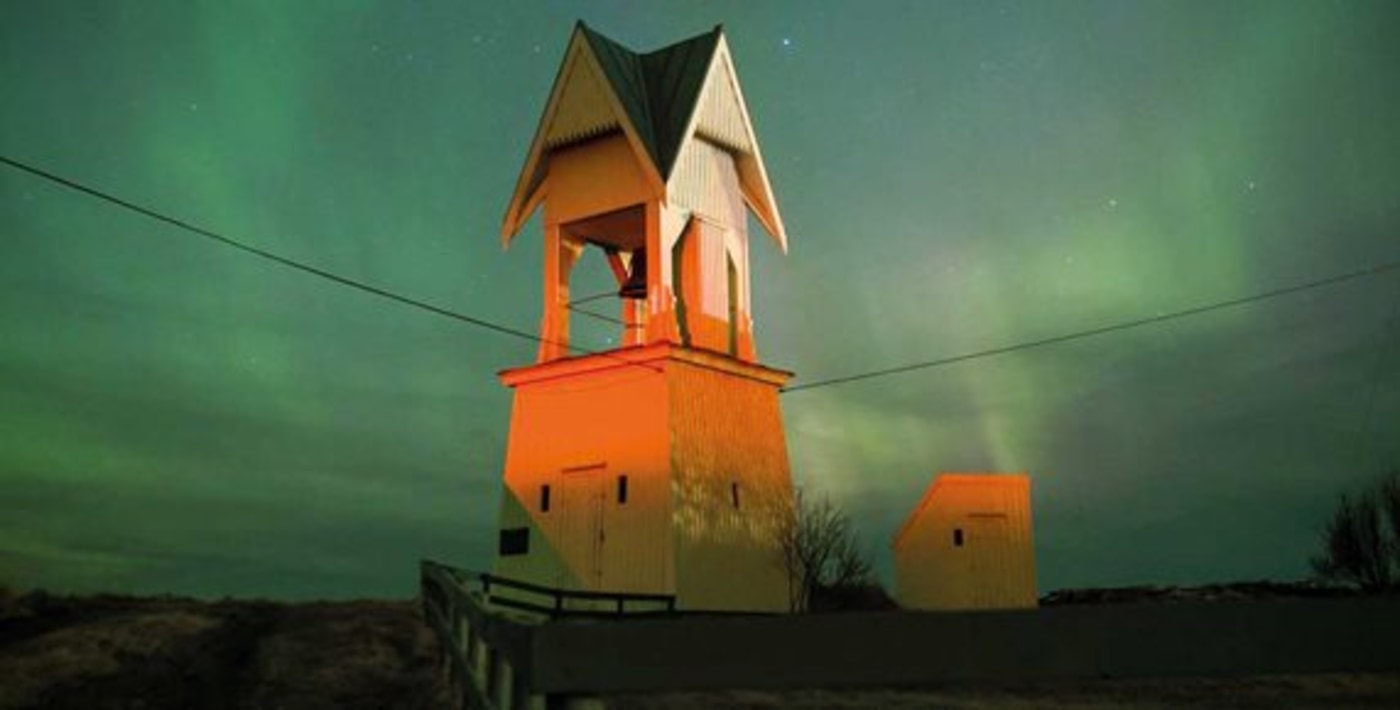 Klokketårn og en himmel full av nordlys. 