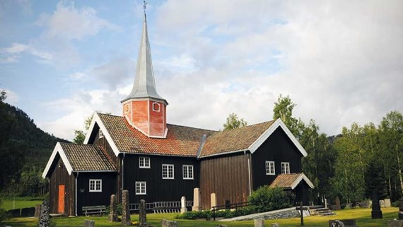 Flesberg stavkirke. Kirken er omgitt av et gjerde av stående gråsteinsheller med ringer der bøndene tjoret hestene sine. 