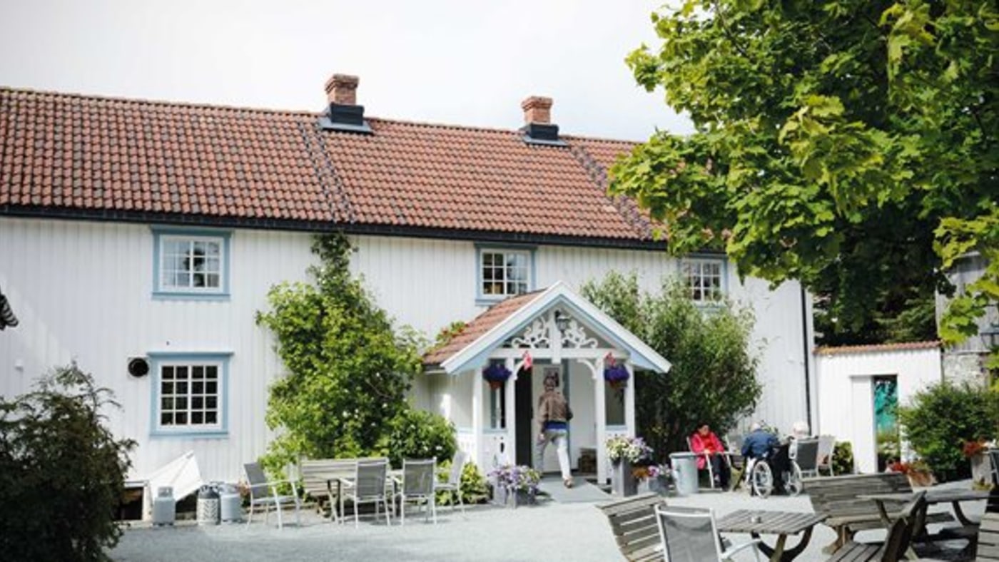 Gammel gård. Uteservering med bord og stoler.
