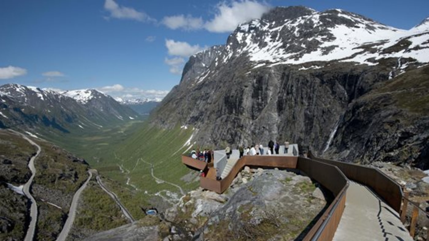 Utsiktsplatform ved Trollstigen. Turister titter på utsikten. 