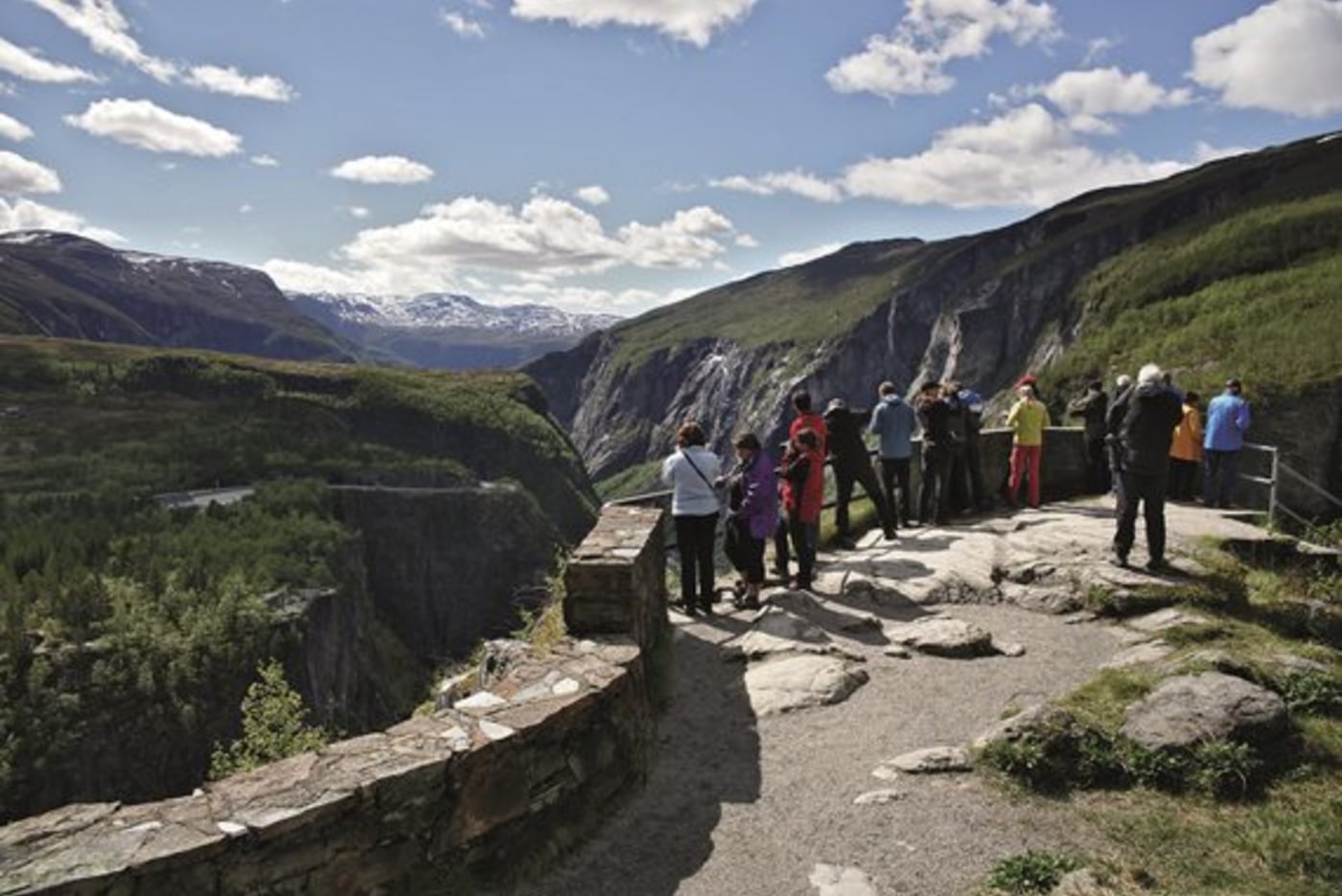 Turister kikker over kanten av stupet ved Fossli og ser ned på Vøringsfossen og Måbødalen. 