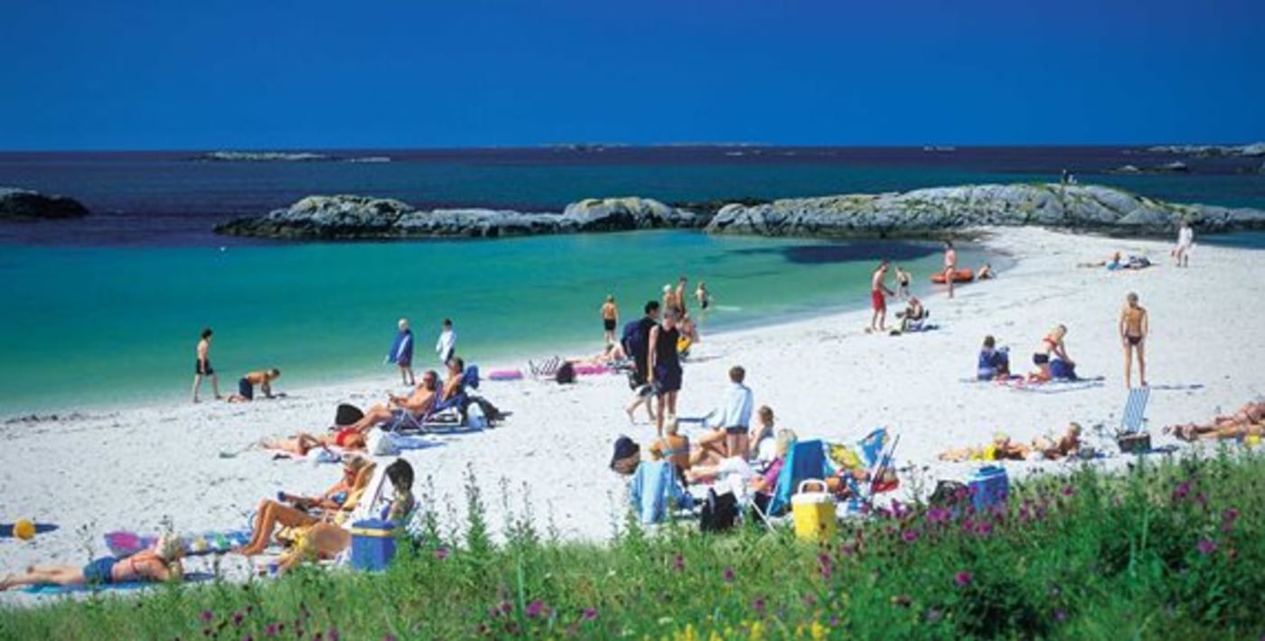 Sandstrand med mange mennesker som bader og soler seg. 