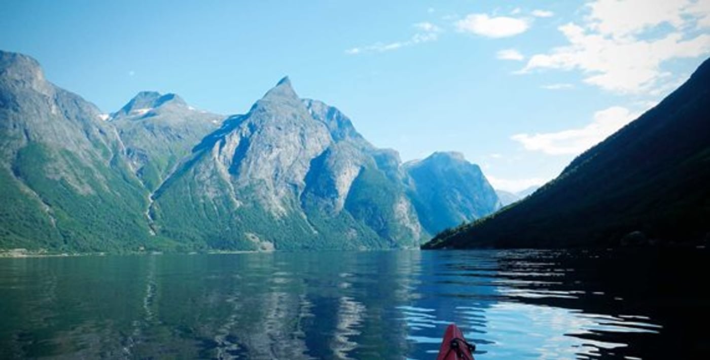 Fjell som stuper ned i vannet er fotografert fra kajakk. 