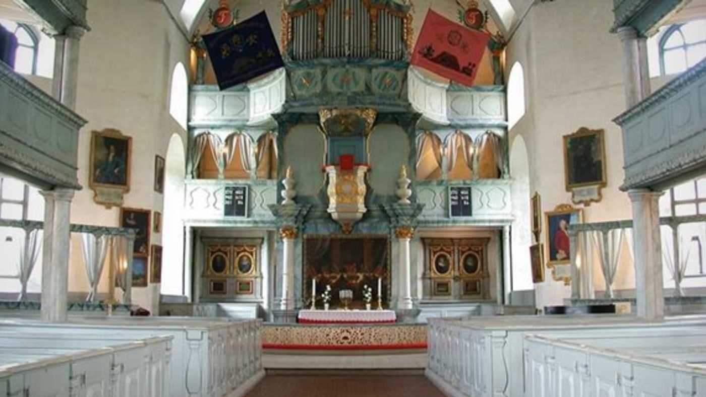 Inne i Røros kirke. Trebenker, søyler, treutskjæring og mektige orgelpiper. 