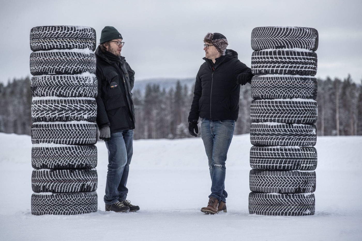 To menn som viser stabler av vinterdekk med både med og uten pigg