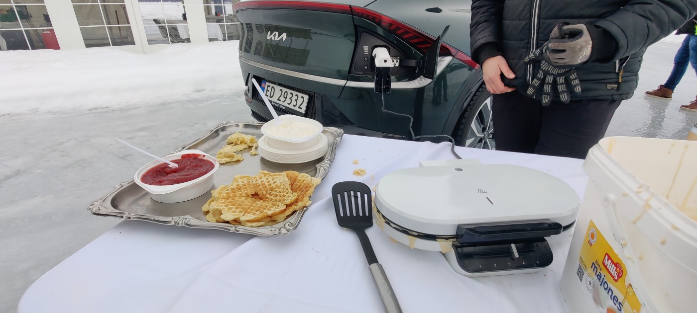 Mann som steker vafler med en bil parkert bak seg