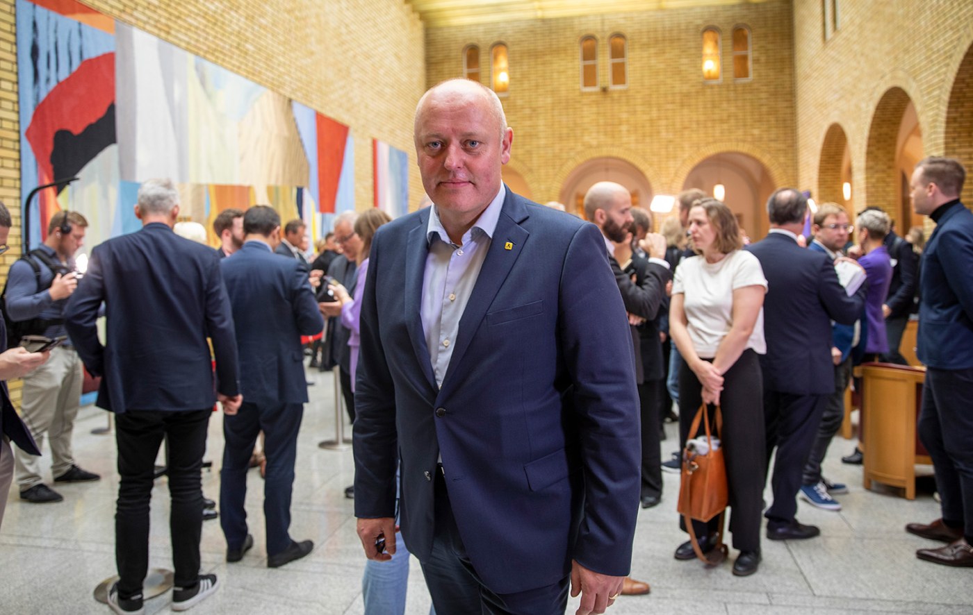 Mann holder dokumenter i stort rom