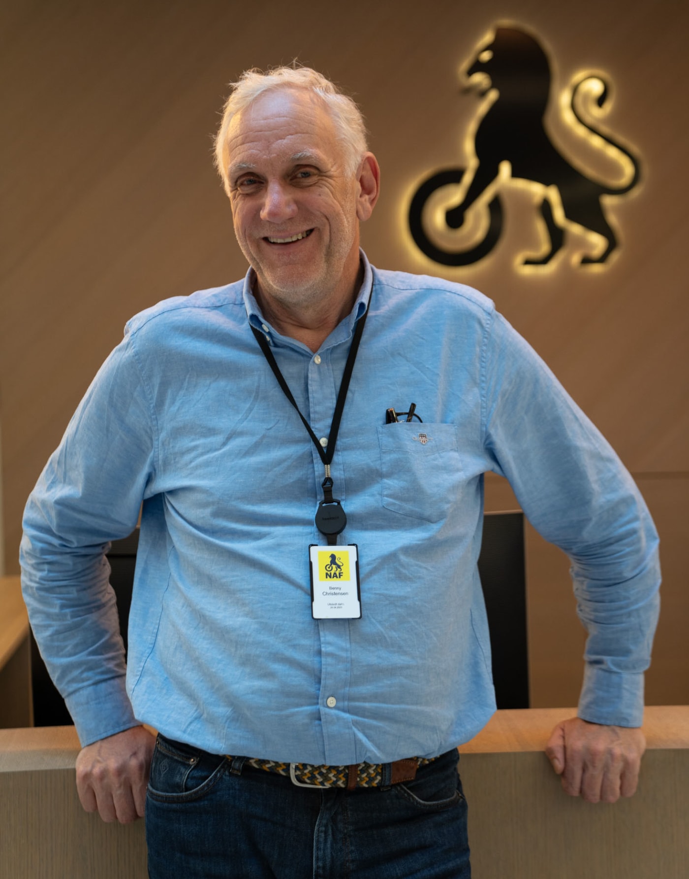 Smilende mann foran vegg med NAF-logo