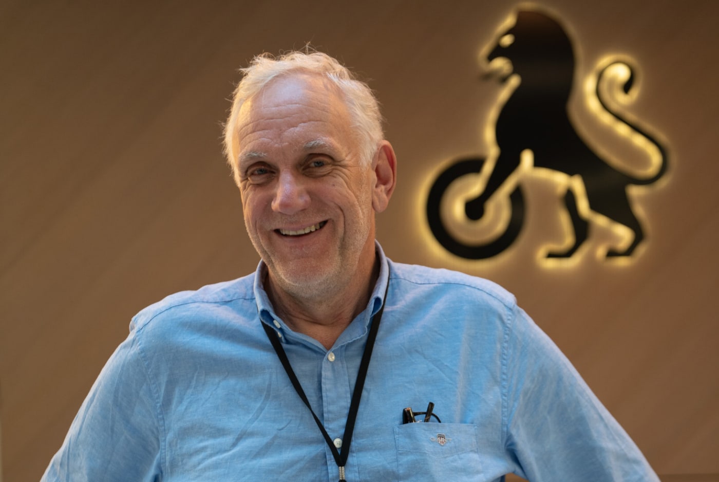 Smilende mann foran vegg med NAF-logo