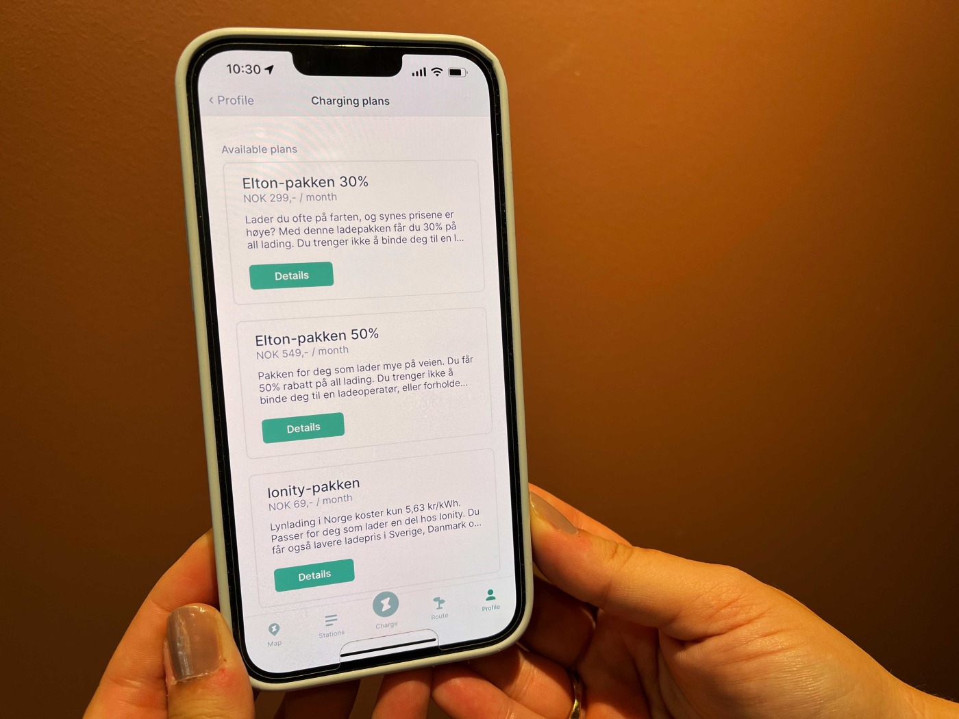 En person holder en mobil som ser på ulike ladepakker fra Elton
