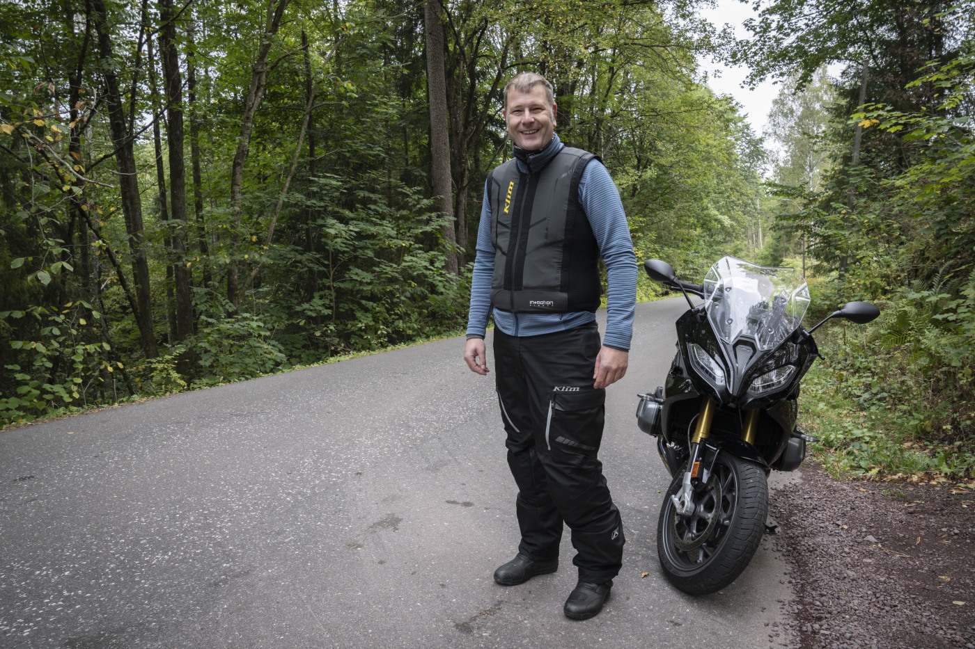 mann står ved motorsykkel på veien