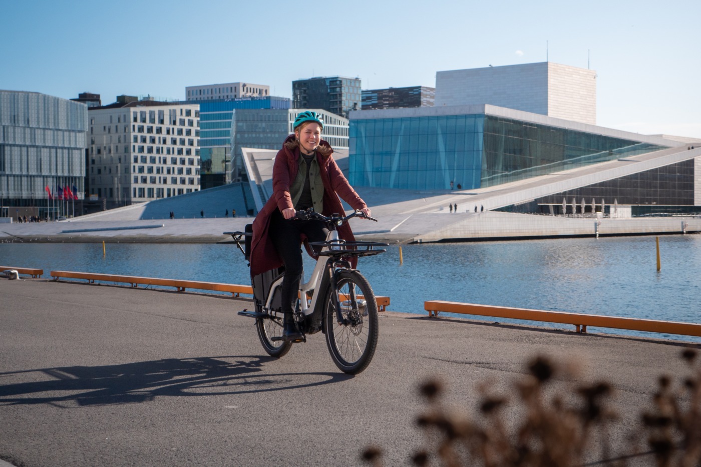 Bildet viser en dame som sykler på en elsykkel på brygga ved Operaen.
