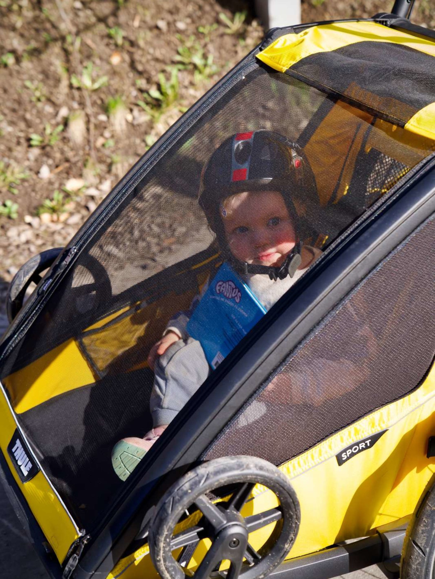 Et barn tester sittedelen i gul Thule Chariot Sport 2