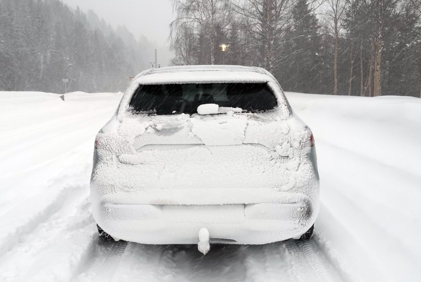 Bildet viser en snødekket bil bakfra langs en snødekket landevei.