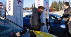 to menn står ved ladestolpe og biler